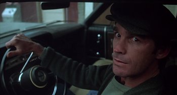 Movie still from “Melvin and Howard” (1980), directed by Jonathan Demme – A man driving a car wearing a hat and a sweater; Close Up shot, High angle