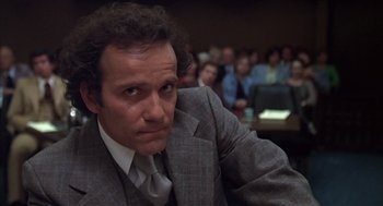 Movie still from “Melvin and Howard” (1980), directed by Jonathan Demme – A man sitting in front of an audience wearing a suit and tie; Close Up shot, Low angle