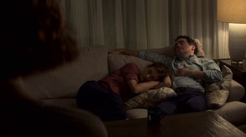 Movie still from “13 Reasons Why” (2017), created by Brian Yorkey – A man and a woman laying on a couch next to each other; Medium shot, High angle