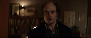 Movie still from “Men & Chicken” (2015), directed by Anders Thomas Jensen – A person wearing a suit and tie; Close Up shot, Over the shoulder angle