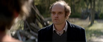 Movie still from “Men & Chicken” (2015), directed by Anders Thomas Jensen – A man in a black jacket is looking at the camera; Close Up shot, Over the shoulder angle