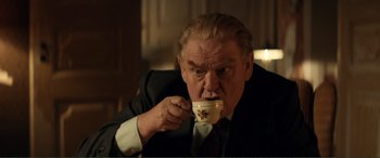 Movie still from “Men & Chicken” (2015), directed by Anders Thomas Jensen – An older man in a suit and tie drinking a cup of coffee; Close Up shot, Low angle