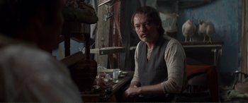 Movie still from “Men & Chicken” (2015), directed by Anders Thomas Jensen – A man sitting at a table in a room; Medium shot, Over the shoulder angle