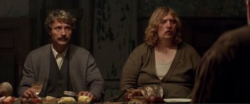 Movie still from “Men & Chicken” (2015), directed by Anders Thomas Jensen – A couple of people sitting at a table with food; Medium shot, Low angle