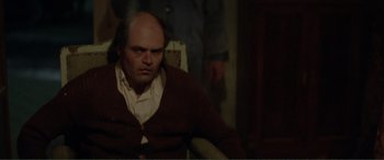 Movie still from “Men & Chicken” (2015), directed by Anders Thomas Jensen – A man with a bald head sitting in a chair; Medium shot, High angle