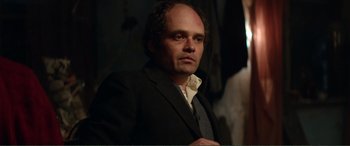 Movie still from “Men & Chicken” (2015), directed by Anders Thomas Jensen – A man in a suit and tie looking at the camera; Medium shot, Over the shoulder angle