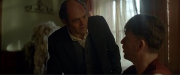 Movie still from “Men & Chicken” (2015), directed by Anders Thomas Jensen – A man in a suit and tie talking to a woman; Medium shot, Over the shoulder angle