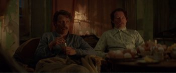Movie still from “Men & Chicken” (2015), directed by Anders Thomas Jensen – Two men sitting on a couch in a living room; Medium shot, High angle