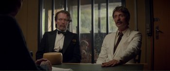 Movie still from “Men & Chicken” (2015), directed by Anders Thomas Jensen – Two men sitting at a table in front of a window; Medium shot, Low angle