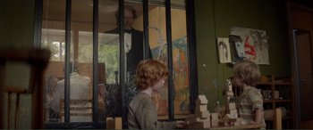 Movie still from “Men & Chicken” (2015), directed by Anders Thomas Jensen – A young boy is playing with blocks in front of an older man; Medium shot, Over the shoulder angle