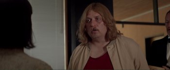 Movie still from “Men & Chicken” (2015), directed by Anders Thomas Jensen – A man with long blonde hair is standing in a room; Close Up shot, Over the shoulder angle
