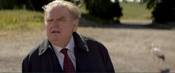 Movie still from “Men & Chicken” (2015), directed by Anders Thomas Jensen – An older man in a black jacket and a red tie; Close Up shot, Over the shoulder angle
