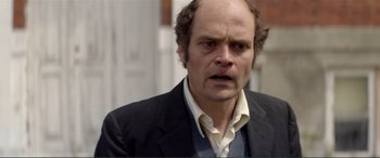 Movie still from “Men & Chicken” (2015), directed by Anders Thomas Jensen – A person wearing a suit and tie; Close Up shot, Over the shoulder angle