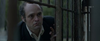 Movie still from “Men & Chicken” (2015), directed by Anders Thomas Jensen – A man standing behind a metal fence looking at the camera; Close Up shot, Low angle
