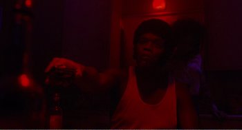 Movie still from “Menace II Society” (1993), directed by Albert Hughes – A man in a white tank top is in a dark room; Close Up shot, Low angle