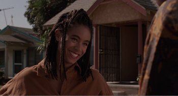 Movie still from “Menace II Society” (1993), directed by Albert Hughes – A woman with dreads smiles for the camera; Close Up shot, Over the shoulder angle