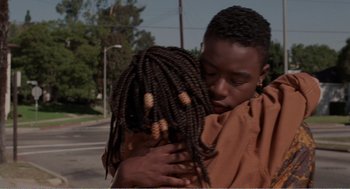 Movie still from “Menace II Society” (1993), directed by Albert Hughes – A woman hugging another woman in front of a street light; Close Up shot, High angle