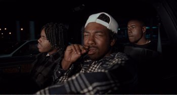 Movie still from “Menace II Society” (1993), directed by Albert Hughes – A group of people sitting in a car at night; Medium shot, High angle