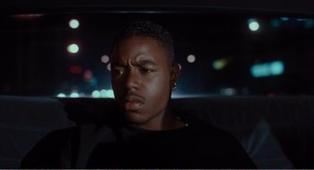 Movie still from “Menace II Society” (1993), directed by Albert Hughes – A man sitting in the back seat of a car at night; Close Up shot, High angle
