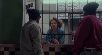 Movie still from “Menace II Society” (1993), directed by Albert Hughes – A woman sitting at a table in front of two men; Medium shot, Over the shoulder angle
