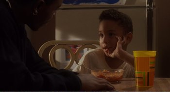 Movie still from “Menace II Society” (1993), directed by Albert Hughes – A man and a boy sitting at a wooden table; Close Up shot, High angle