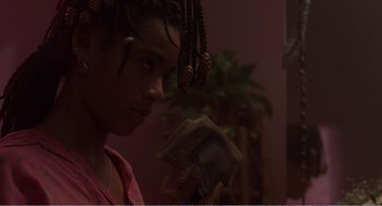Movie still from “Menace II Society” (1993), directed by Albert Hughes – A young woman with dreadlocks looking at her cell phone; Close Up shot, Over the shoulder angle