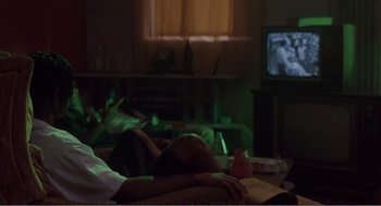 Movie still from “Menace II Society” (1993), directed by Albert Hughes – Two people sitting in a living room watching television; Medium shot, Over the shoulder angle