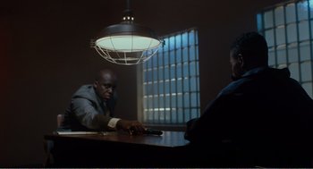 Movie still from “Menace II Society” (1993), directed by Albert Hughes – Two men sitting at a table in front of a window; Medium shot, Low angle