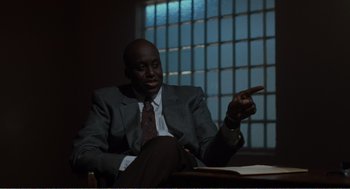 Movie still from “Menace II Society” (1993), directed by Albert Hughes – A man in a suit and tie sitting in front of a window; Medium shot, Low angle