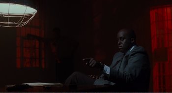 Movie still from “Menace II Society” (1993), directed by Albert Hughes – A man in a suit sitting in front of a table; Medium shot, Low angle