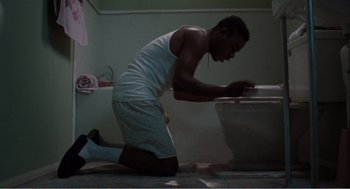 Movie still from “Menace II Society” (1993), directed by Albert Hughes – A man kneeling on the floor in front of a toilet; Medium shot, Low angle