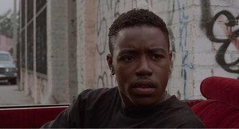 Movie still from “Menace II Society” (1993), directed by Albert Hughes – A person wearing a black t - shirt; Close Up shot, High angle