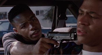 Movie still from “Menace II Society” (1993), directed by Albert Hughes – A man holding a gun in his hand while sitting in a car; Close Up shot, Over the shoulder angle