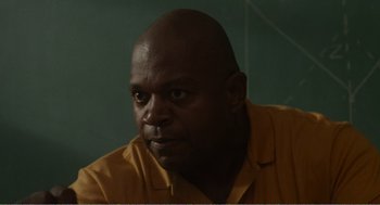 Movie still from “Menace II Society” (1993), directed by Albert Hughes – A man with a bald head wearing an orange shirt; Close Up shot, Over the shoulder angle