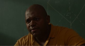 Movie still from “Menace II Society” (1993), directed by Albert Hughes – A man in a yellow shirt is looking at the camera; Close Up shot, Over the shoulder angle