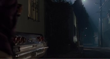 Movie still from “Menace II Society” (1993), directed by Albert Hughes – A car parked in front of a building at night; Wide shot, Low angle