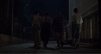 Movie still from “Menace II Society” (1993), directed by Albert Hughes – A group of people walking down a sidewalk at night; Wide shot, Low angle