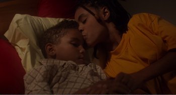 Movie still from “Menace II Society” (1993), directed by Albert Hughes – A woman and a boy laying in a bed kissing; Close Up shot, High angle