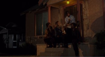 Movie still from “Menace II Society” (1993), directed by Albert Hughes – A group of people sitting on a porch at night; Wide shot, Low angle