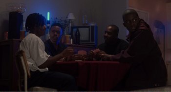 Movie still from “Menace II Society” (1993), directed by Albert Hughes – A group of people sitting around a table; Medium shot, High angle