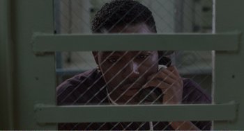 Movie still from “Menace II Society” (1993), directed by Albert Hughes – A man sitting in front of a window talking on a phone; Close Up shot, High angle