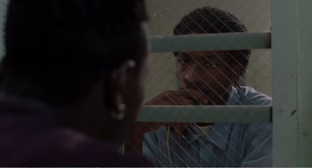 Movie still from “Menace II Society” (1993), directed by Albert Hughes – A man and a woman looking through a fence; Close Up shot, Over the shoulder angle
