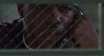 Movie still from “Menace II Society” (1993), directed by Albert Hughes – A person behind bars looking through bars; Close Up shot, High angle