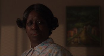 Movie still from “Menace II Society” (1993), directed by Albert Hughes – A woman standing in front of a painting in a living room; Close Up shot, Over the shoulder angle