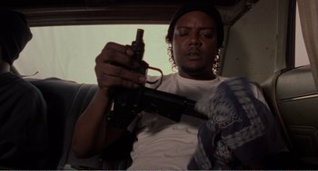 Movie still from “Menace II Society” (1993), directed by Albert Hughes – A man holding an ar - 1 5 style gun in his hand; Medium shot, Low angle
