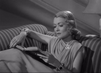A woman sitting on a couch reading a book
