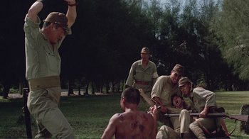 Movie still from “Merry Christmas Mr. Lawrence” (1983), directed by Nagisa Ôshima – A group of men sitting in the grass; Wide shot, Over the shoulder angle
