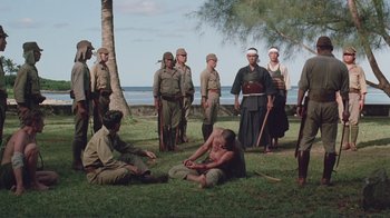 Movie still from “Merry Christmas Mr. Lawrence” (1983), directed by Nagisa Ôshima – A group of men standing and sitting in the grass; Wide shot, High angle