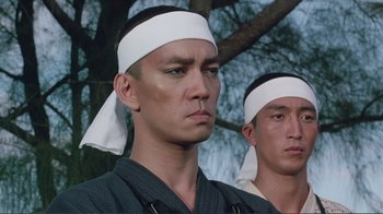 Movie still from “Merry Christmas Mr. Lawrence” (1983), directed by Nagisa Ôshima – Two young men wearing bandannas standing next to each other; Close Up shot, Low angle