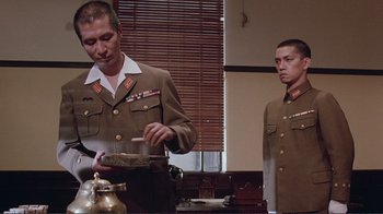 Movie still from “Merry Christmas Mr. Lawrence” (1983), directed by Nagisa Ôshima – Two men dressed in military uniforms are preparing a meal; Medium shot, Low angle
